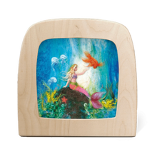 Silhouette of a mermaid resting on a rock underwater, surrounded by jellyfish and a goldfish