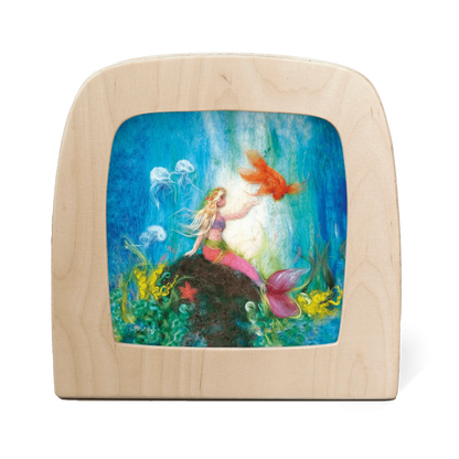Silhouette of a mermaid resting on a rock underwater, surrounded by jellyfish and a goldfish
