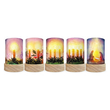 Five cylindrical pillar candle shades with light wood bases, each featuring a different warm-toned nativity or candle-themed illustration on the wrapper, shown against a plain white background.
