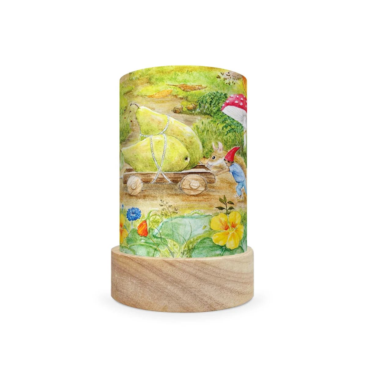 A cylindrical table lamp with a light natural wood base and a printed wraparound cylinder featuring a whimsical garden scene with a pear cart, rabbit, bird, flowers, and mushrooms, shown on a plain white background.