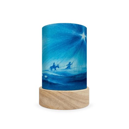 Decorative lamp with scene of Mary and Joseph following a star on a wooden base on a white background