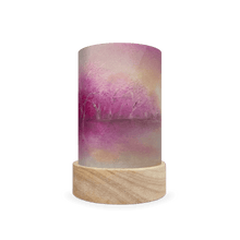 Cylindrical lamp with a wooden base and gradient purple to pink landscape on a white background