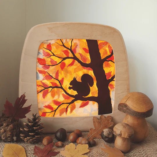 Decorative toverlux light with autumn design featuring a squirrel and tree, surrounded by fall-themed decor.