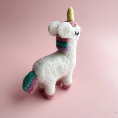 Stuffed unicorn toy with a colorful horn and tail on a pink background