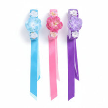 Teal, fuschia, and purple velvet pansy headbands on a white background