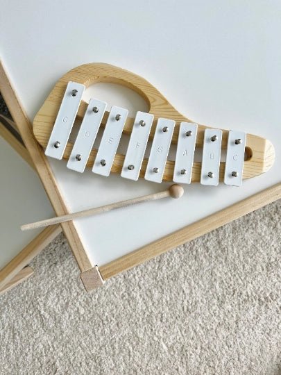 Wooden xylophone with white keys on a light gray surface
