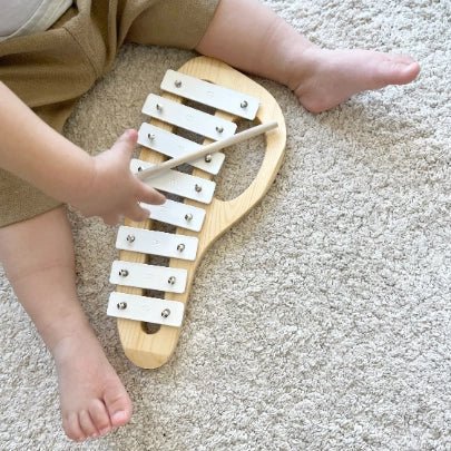 Child playing with a wooden xylophone on a carpeted floor