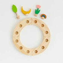 Wooden ring with holes and small colorful wooden figures on a light gray background