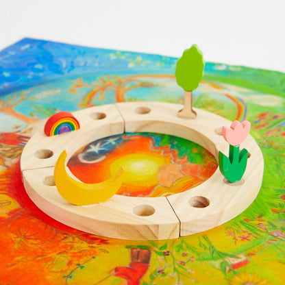 Wooden birthday ring with circular design featuring a moon, sun, rainbow, tree, and flower on a colorful background.