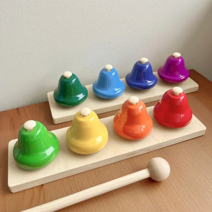 Colorful wooden bell set with a mallet on a wooden surface