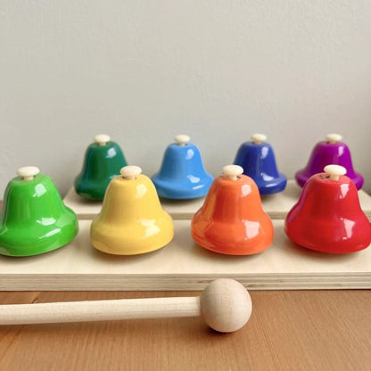 Colorful wooden bells with a wooden mallet on a light gray background