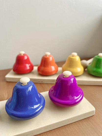 Set of colorful bells on a wooden surface with a neutral background