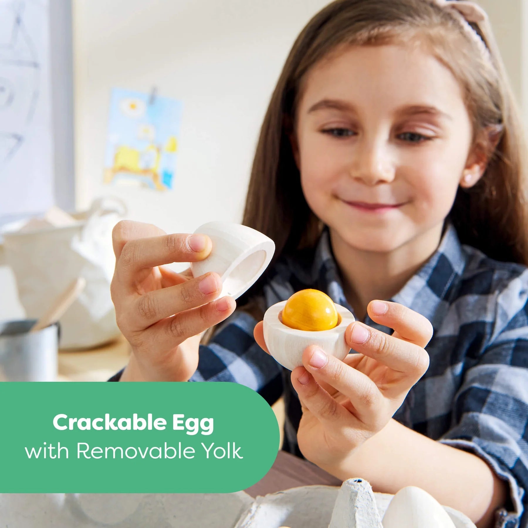 Child holding a toy egg with a removable yellow yolk, with a green label at the bottom.