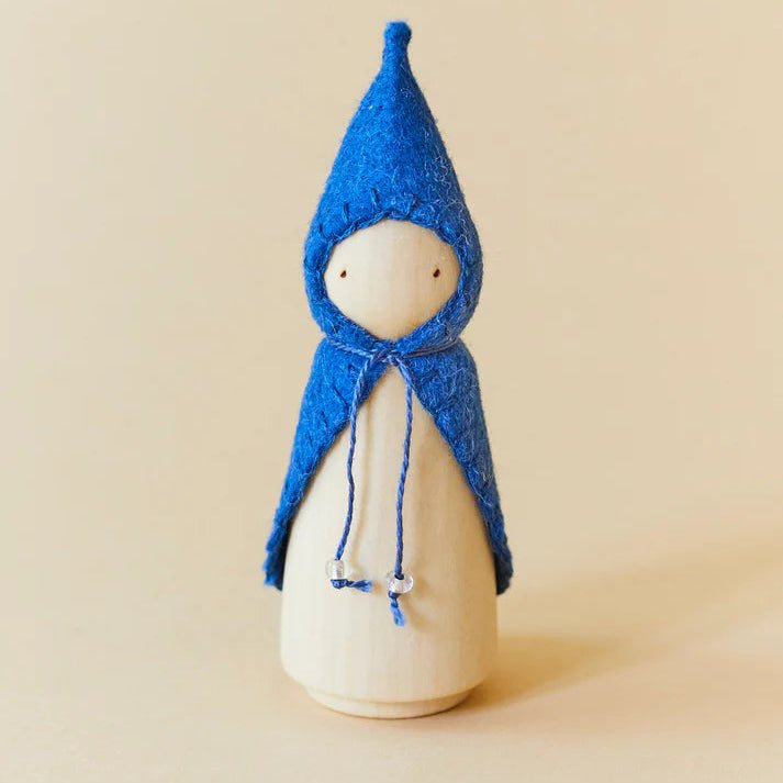 Wooden gnome figure with a blue hood and coat on a beige background