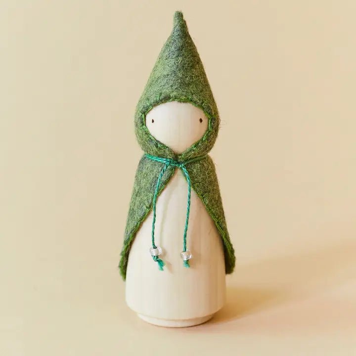 Wooden gnome figure with a green hood and coat on a beige background