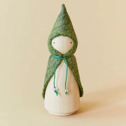 Wooden gnome figure with a green hood and coat on a beige background