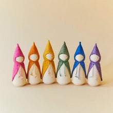 Line of wooden figures with different colored pointy hats on a beige background