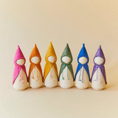 Line of wooden figures with different colored pointy hats on a beige background