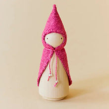 Wooden gnome figure with a pink hood and coat on a beige background