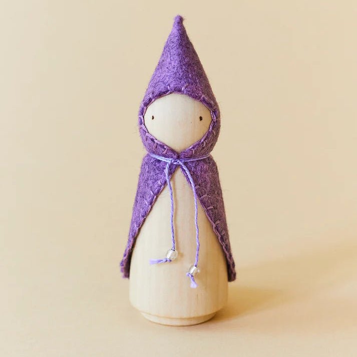 Wooden gnome figure with a purple hood and coat on a beige background