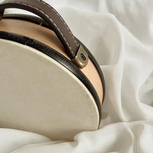 Close-up of a wooden drum with brown leather handle on a white fabric background