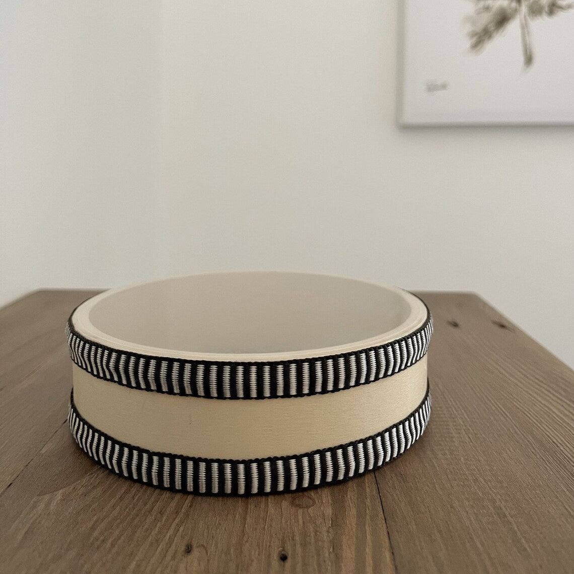 Wooden drum with black and white trim on a wooden surface