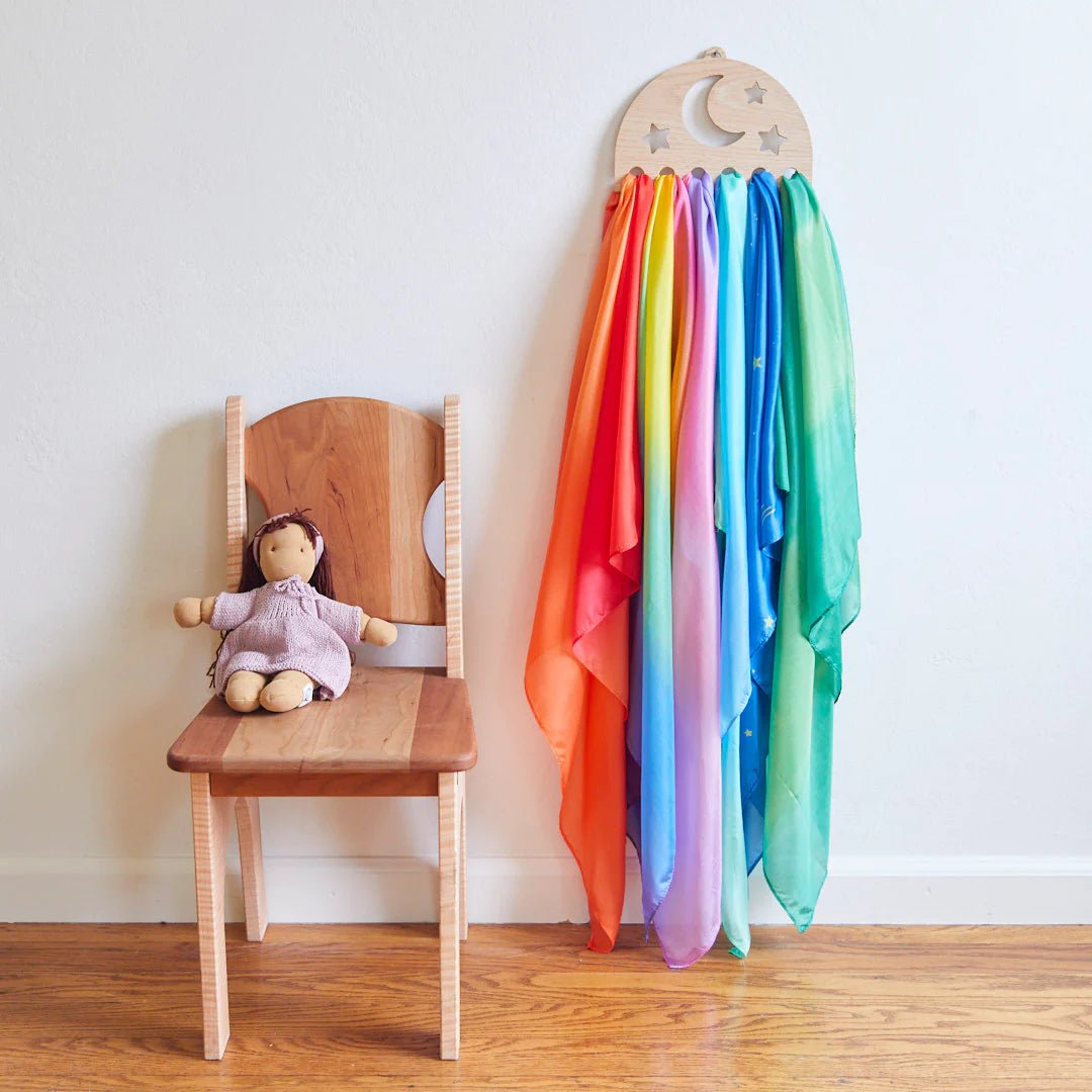 Star-shaped silk display hanging on a wall next to a chair with a doll.